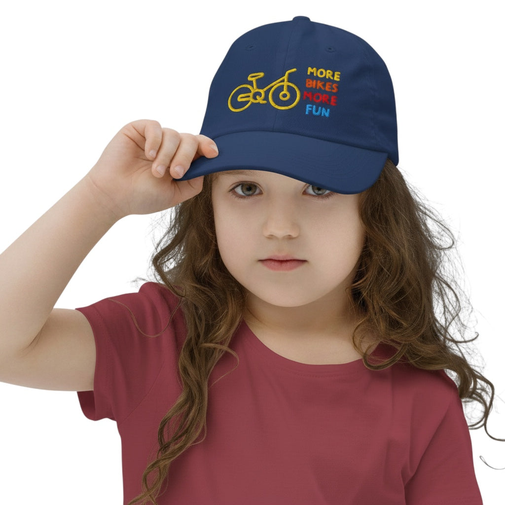 Young girl wearing a navy blue Bikes Make Me Happy cotton baseball cap with More Bikes More Fun embroidery