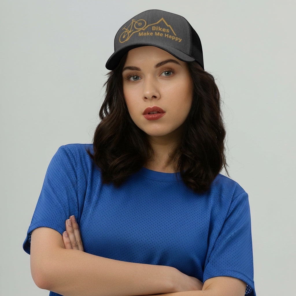 A woman wearing a Bikes Make Me Happy charcoal grey mid-profile trucker hat with a mountain and bike graphic.