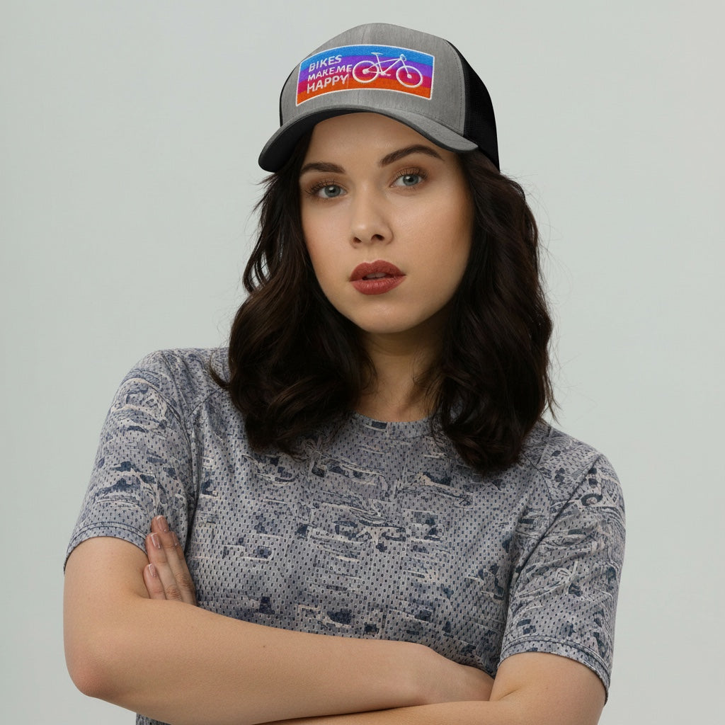 Woman wearing a Bikes Make Me Happy grey and black trucker hat with a colorful embroidered bicycle badge