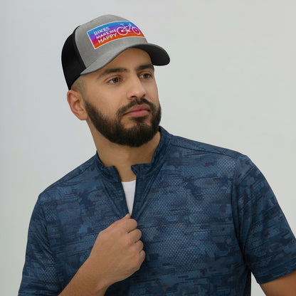 Bikes Make Me Happy trucker hat with grey front, black mesh back, and colorful embroidered cycling badge on a man.